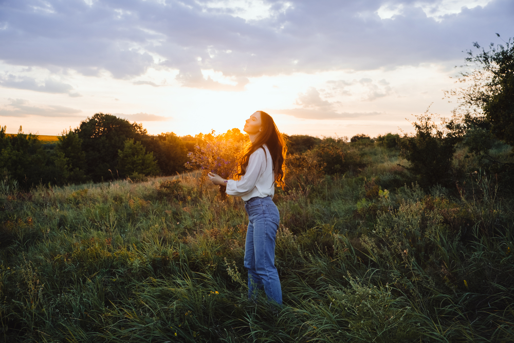 Healing Power of, Benefits Of Ecotherapy, Nature Impact Wellbeing. Happy young woman with long hair and a bouquet of wild flowers enjoy nature and life at sunset.