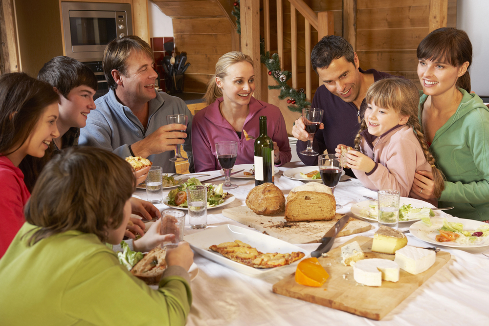 Two Familes Enjoying Meal In Alpine Chalet Together